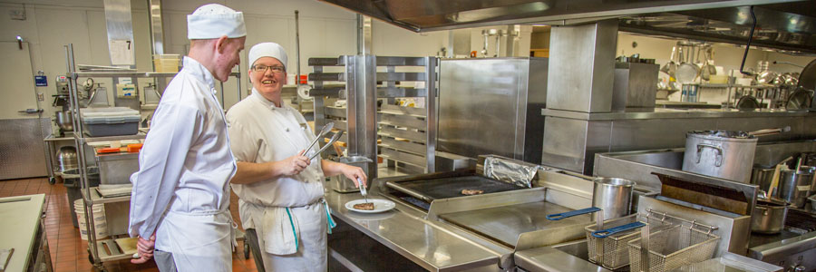 teacher and student in a kitchen, checking temperature of beef